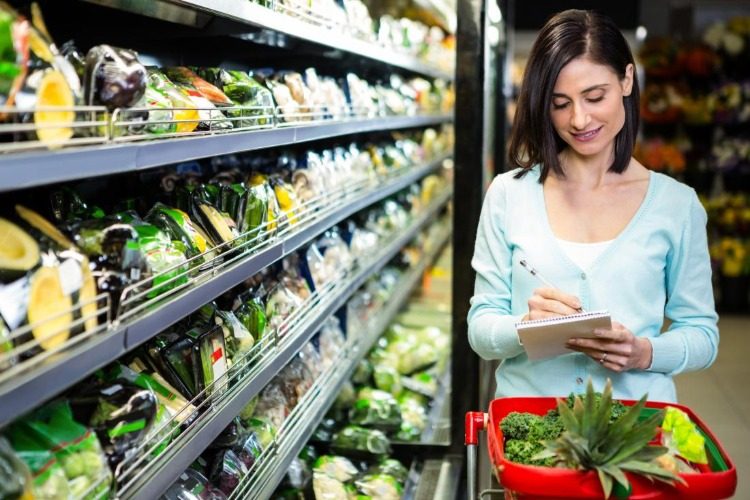woman writes grocery list at vegetable stand for a 500 calorie diet