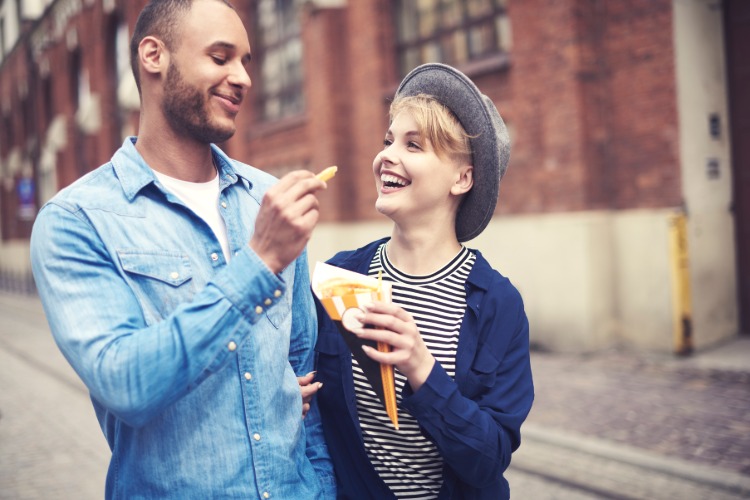 happy couple eating fries while standing