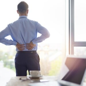 junger mann im büro hält seinen rücken wegen schmerzen