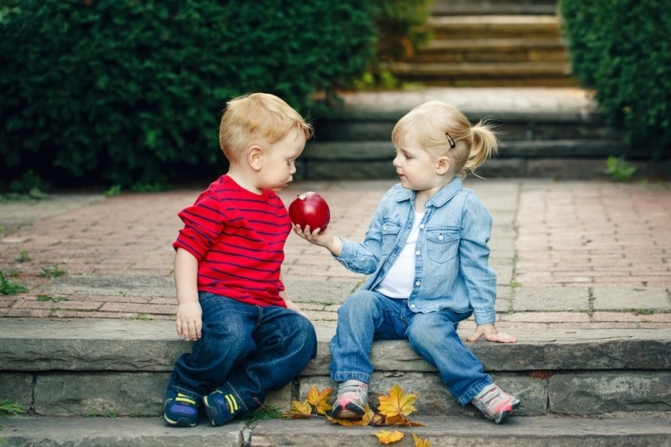 kleines mädchen schenkt kleinem jungen einen apfel altruistisches verhalten erforschen