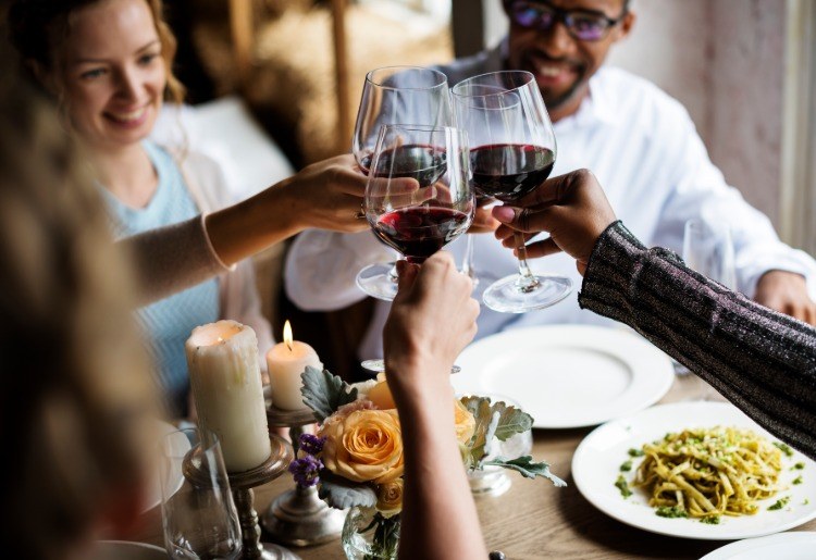 menschen in restaurant trinkspruch ausbringen große weingläser rotwein