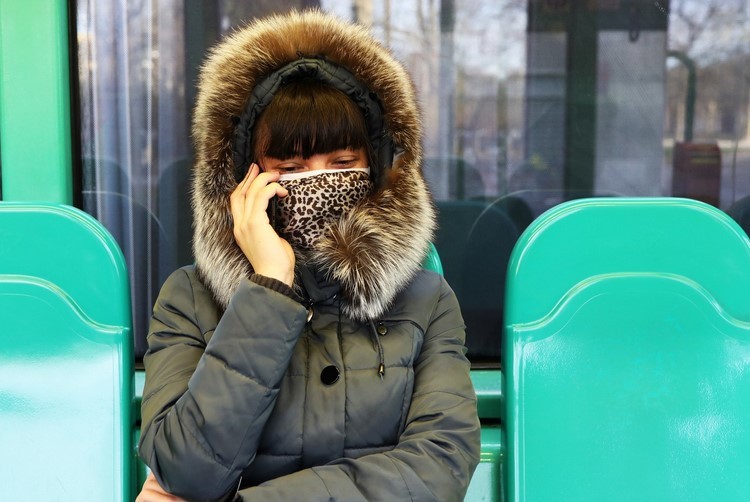 Woman wearing cloth mask and waiting at the bus stop