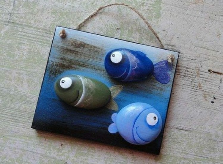 Schöne Geschenkidee - Fische aus Steinen auf einem bemalten Holzbrett zum Aufhängen als Wanddeko