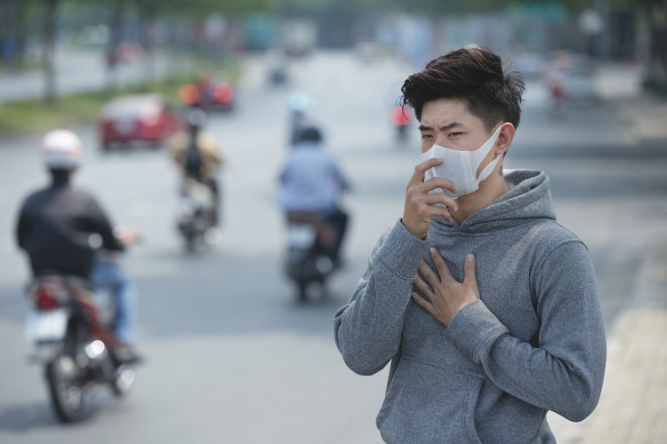 china junger mann mit schutzmaske hält sich an brust corona virus auswirkungen