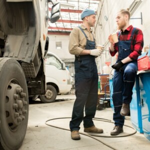 fahrer und mechaniker trinken kaffee in werkstatt