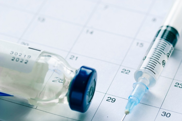grippeimpfung mit spritze und glasflasche auf kalender als maßnahme gegen coronavirus