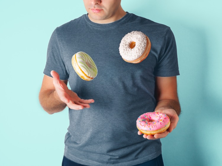 mann jongliert mit donuts kalorienreiche ernährung meiden wegen diabetes und herzerkrangungen