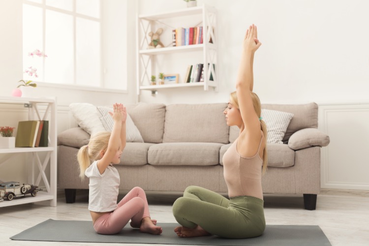 mutter und ihre tochter machen yoga übungen zusammen im wohnzimmer