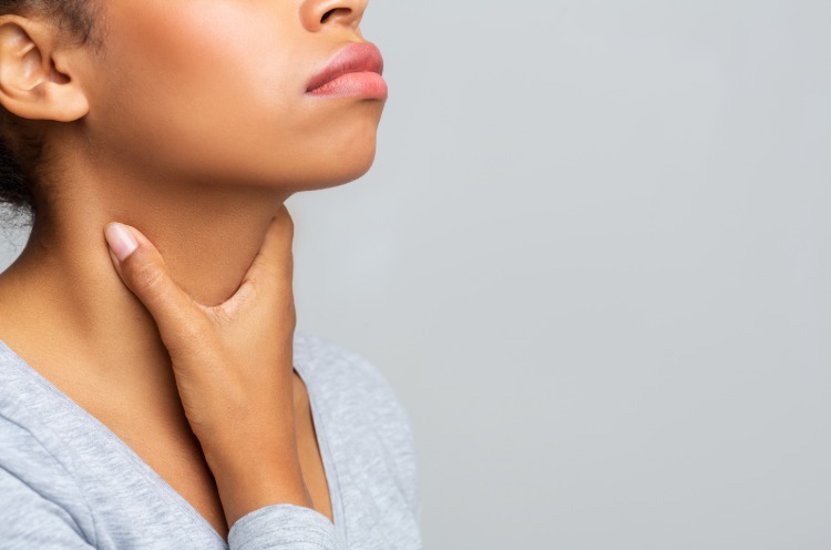 weibliche person hält sich am hals wegen halsschmerzen aufgrund corona virus