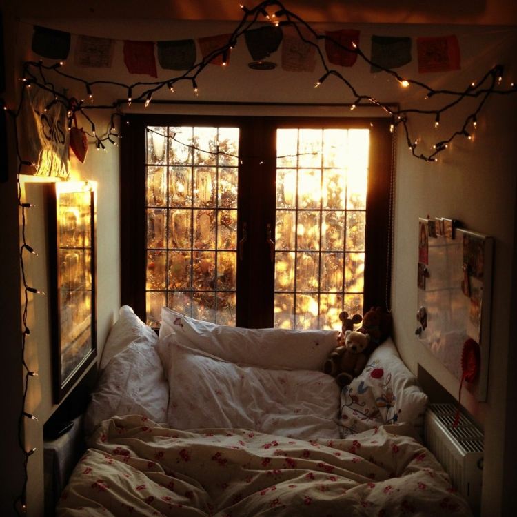 Small alcove for sleeping by the window decorated with fairy lights
