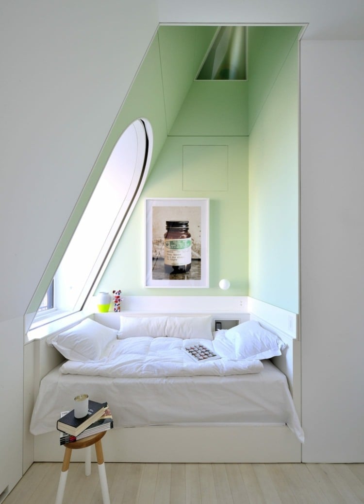 Design cute sleeping alcoves under a sloping roof and with light green wall paint
