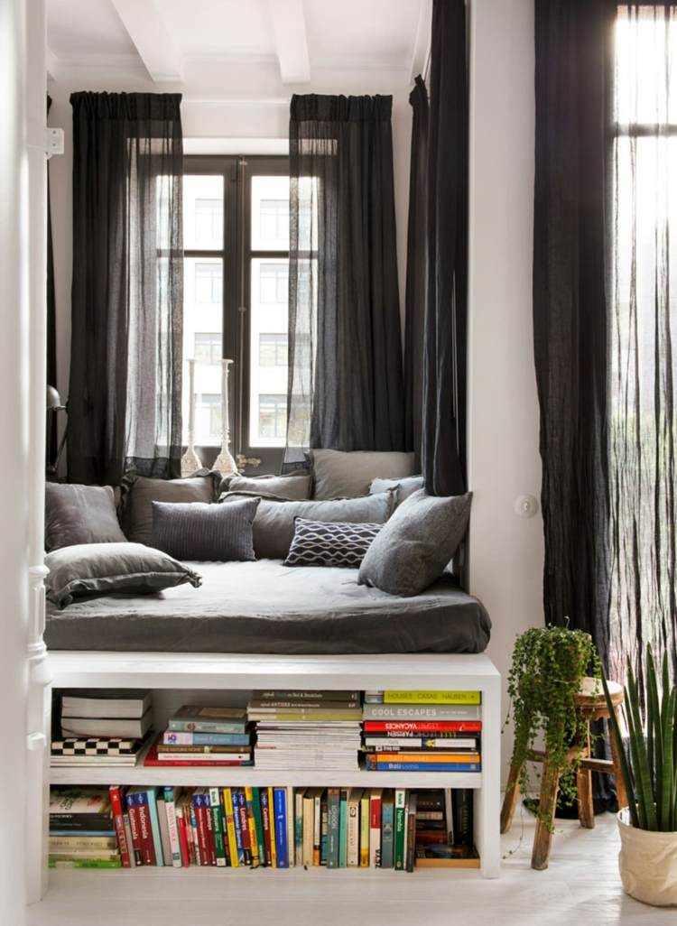 Black and white alcove with pillows on a pedestal and bookcase