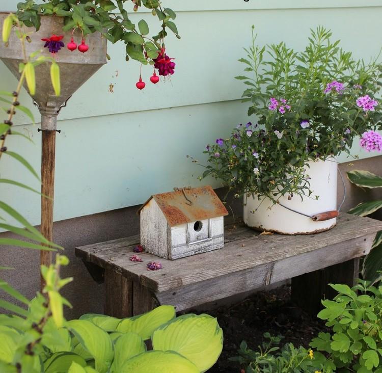 Vintage Garten mit Blumentopf aus Blechdose und alter Hausfigur