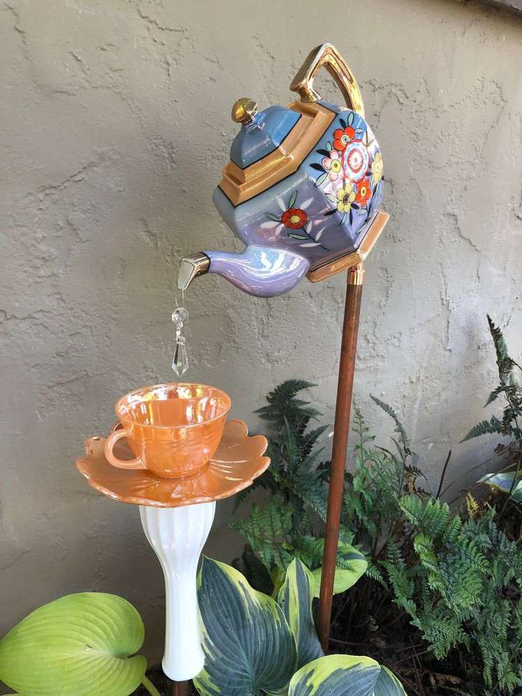 Vintage garden decoration made of teapot and teacup in a flower bed