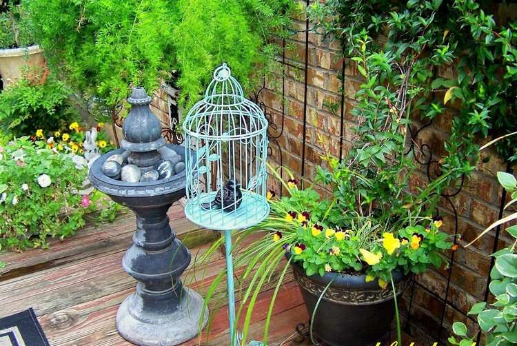Vintage garden decoration with bird cage and homemade bird figure made of clay