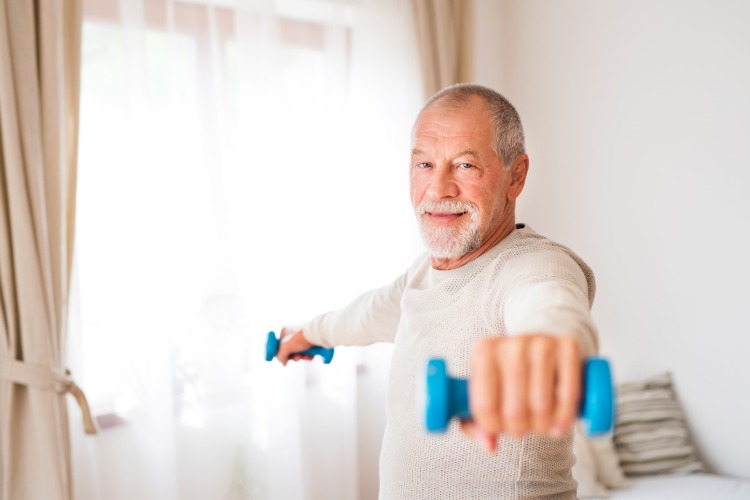älterer mann senior mit leichten gewichten übt zu hause home workout männer