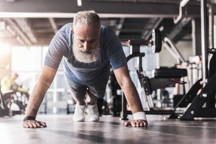 bärtiger mann macht liegestützen im fitnessraum bauch weg training männer ab 50