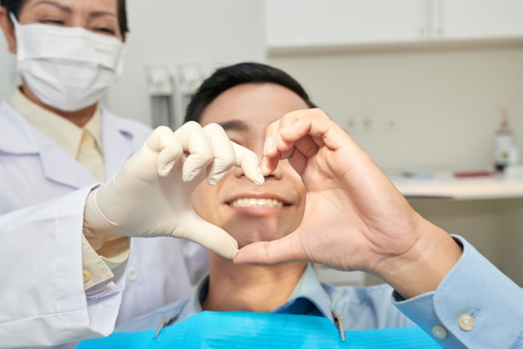 fröhlicher patient und zahnärztin während #zahnarztbesuch herz geste mit händen zeigen