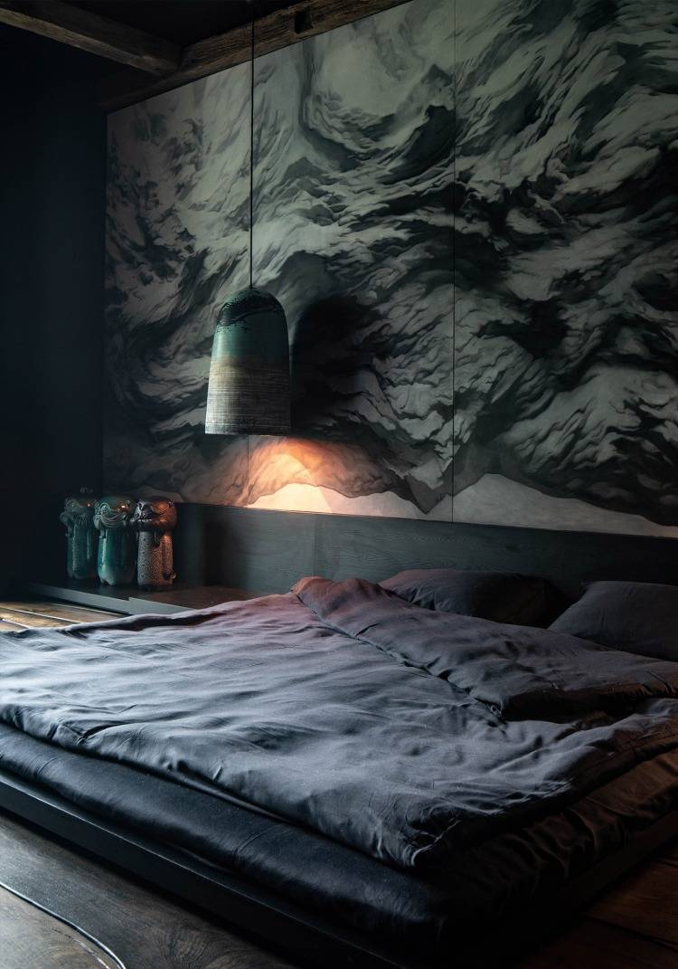 hauptschlafzimmer mit kopfteil in dunklen grautönen und malerischer wand als klippe aus lehm
