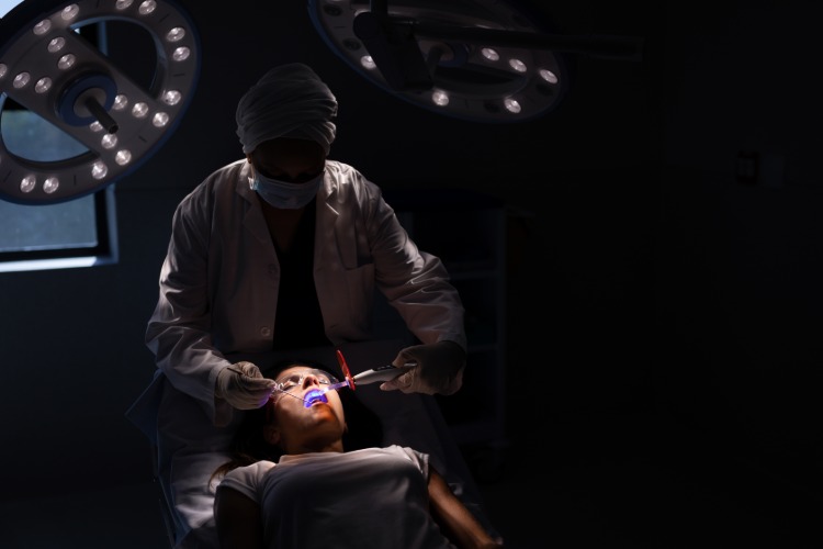 im dunklen raum durchgeführte zahnärztliche behandlung von patientim mit angst vor zahnarzt
