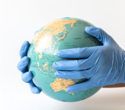 mann mit gummihandschuhen hält globus in den händen