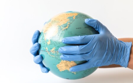 mann mit gummihandschuhen hält globus in den händen