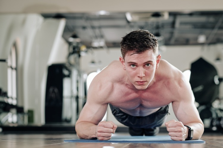 motivierter junger mann plank übung ausführen männer brust training zuha...