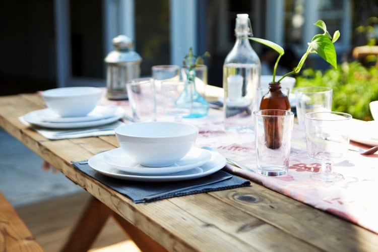 rustic wooden table with table runner dishes and cutlery decoration in the garden