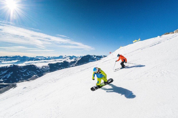 snowboard und skifahrer abfahrt auf roter piste im sommer
