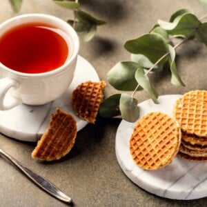 tee in weißer tasse mit zucker waffeln und eukalyptusplätter