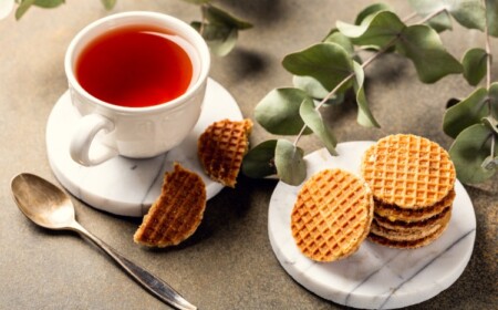 tee in weißer tasse mit zucker waffeln und eukalyptusplätter