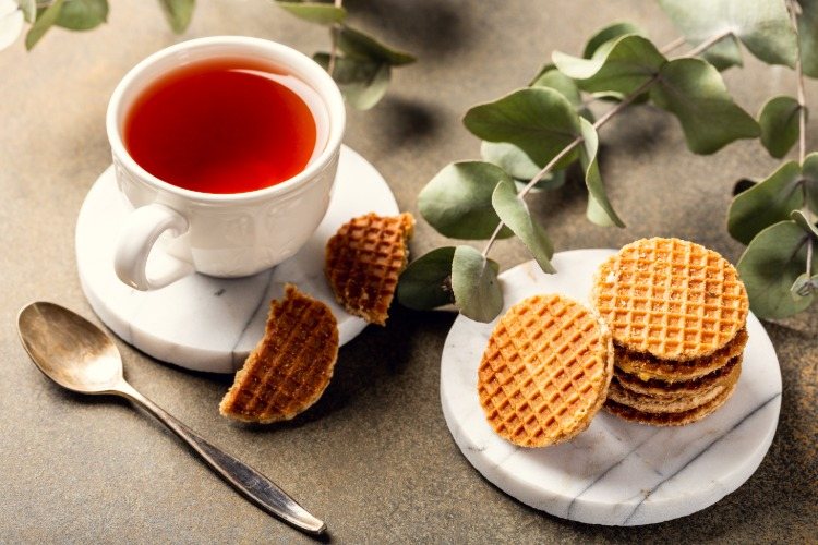 tea in white cup with sugar waffles and eucalyptus leaves