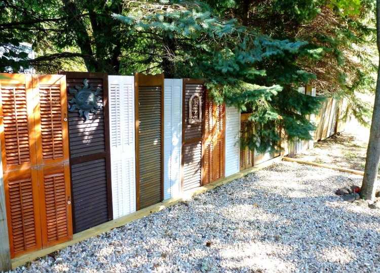 different colors of old shutters built as a fence in the garden
