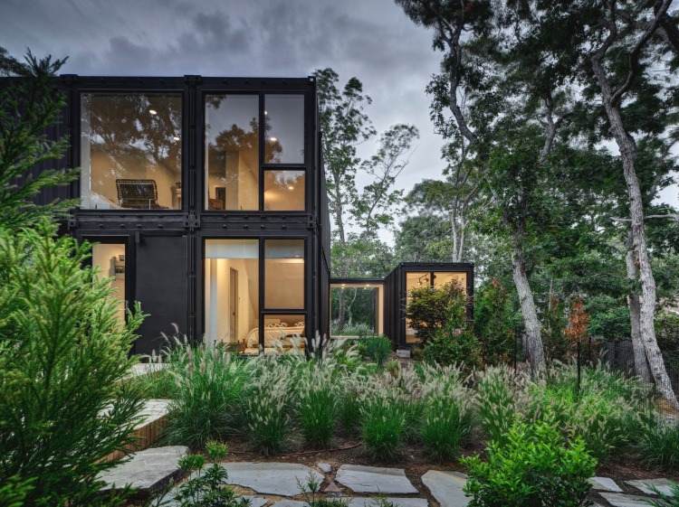 beleuchtetes containerhaus in schwarz mit gartenweg aus naturstein modernes design