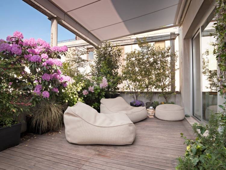 bodenbelag mit terrassendielen holz auf bepflanztem balkon mit polstermöbeln