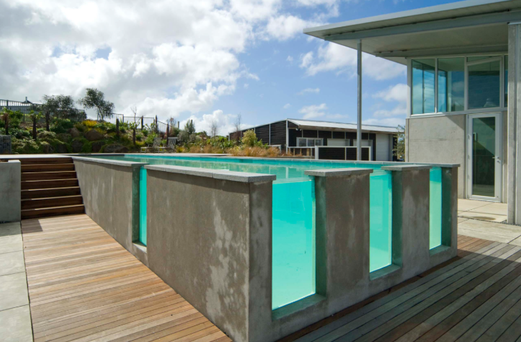 freistehender pool aus beton mit durchsichtigen wänden auf einer außenterrasse installiert