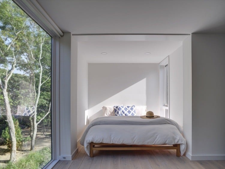 großes glasfenster im hauptschlafzimmer mit weißen wänden und laminatboden