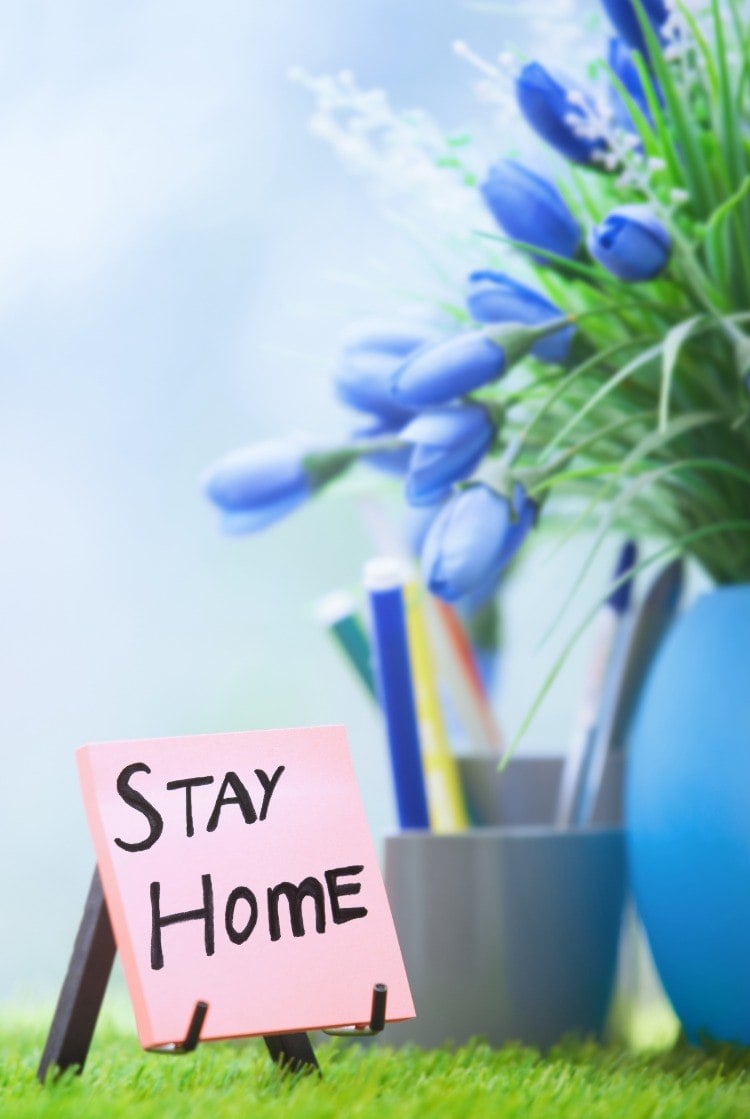 haftnotiz mit stay at home wegen sars coronavirus schrift neben blaue blumen in vase