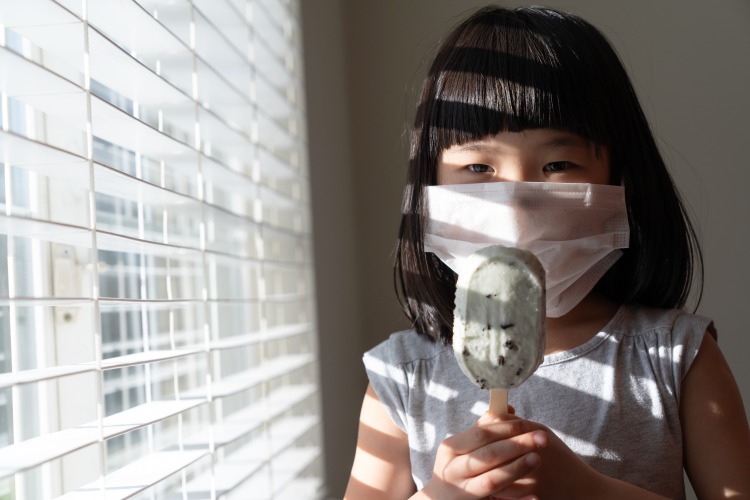 kind mit eis zuhause soziale distanz während corona pandemie im sommer