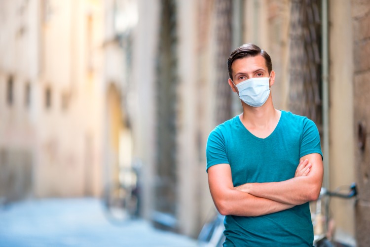 mann mit gesichtsmaske steht auf der straße in italien während coronavirus pandemie