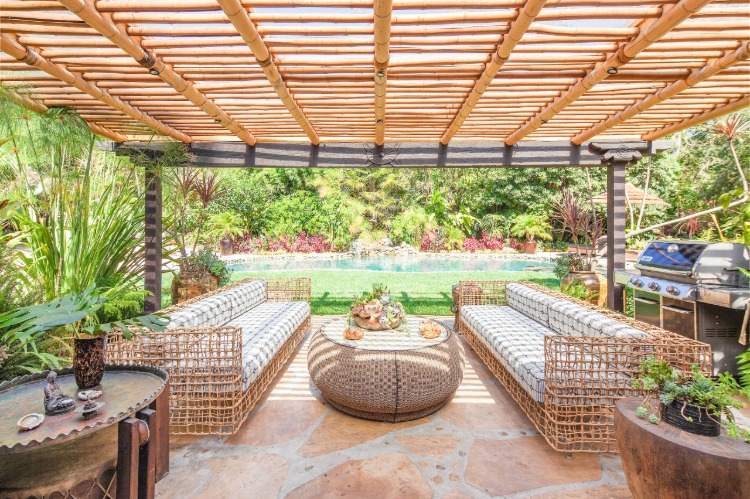 sonnige außenterrasse mit designer möbeln in asiatischem stil mit pergola aus bambus und naturstein boden