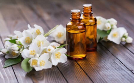 Reines äthersiches Jasminöl in Flaschen und weiße Jasminblüten