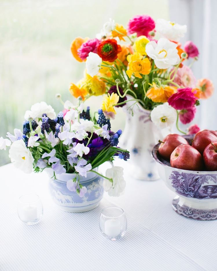 Sommerdeko mit Blumen in Vasen und Teetassen