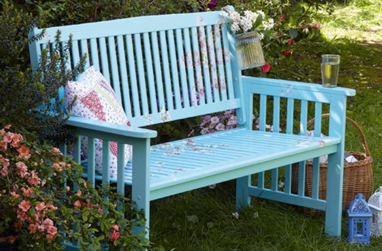 Position light blue garden bench upcycling with decoration made of flowers and pillows outdoors