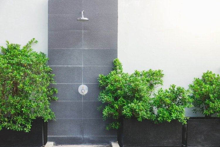 minimalistisches design für außendusche mit grauen fliesen und grünen pflanzen als akzent in der gartengestaltung