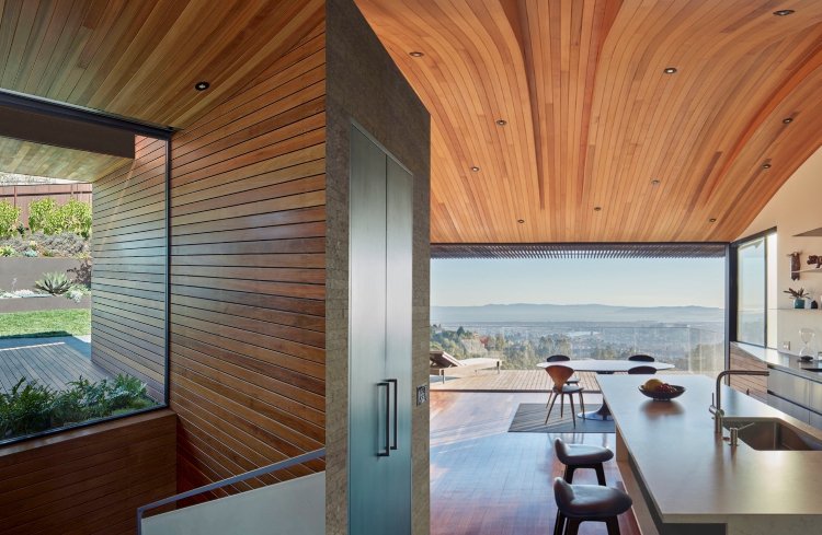 moderne Küche mit Kochinsel und Holzdecke mit Dachfenster und Glasfronten