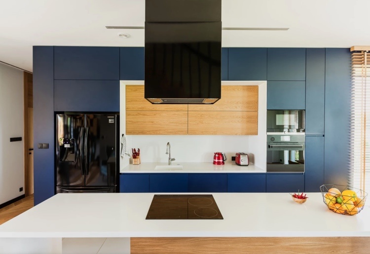 moderne Küche mit blauen Fronten und Holz Oberschränken weiße Arbeotsplatte und Rückwand als Kontrast