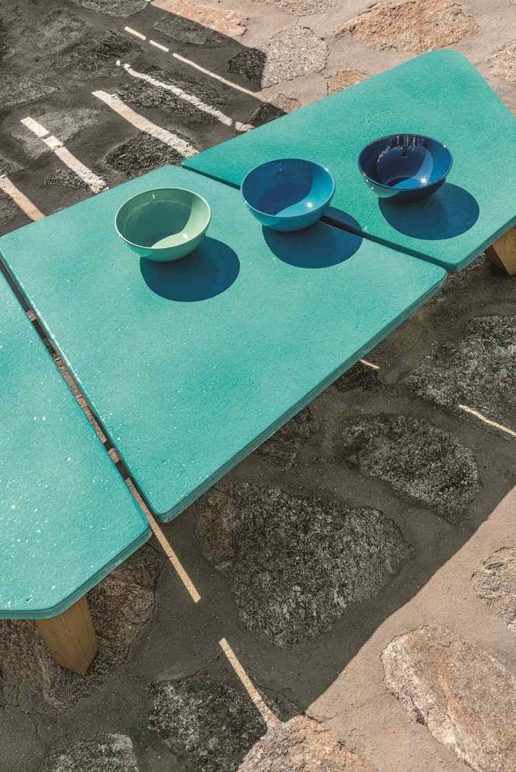 niedriger tisch mit grünen platten und modernen formen auf steinboden