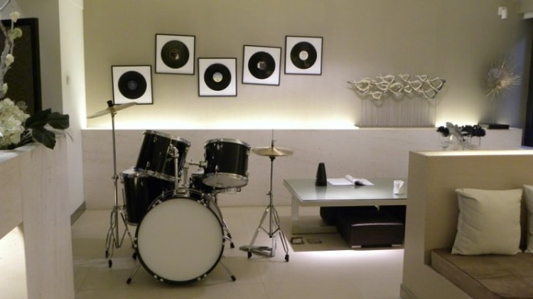 schlagzeug und schalplatten an der wand im musikzimmer einrichten stilvolle gestaltung in weiß mit dezenter beleuchtung