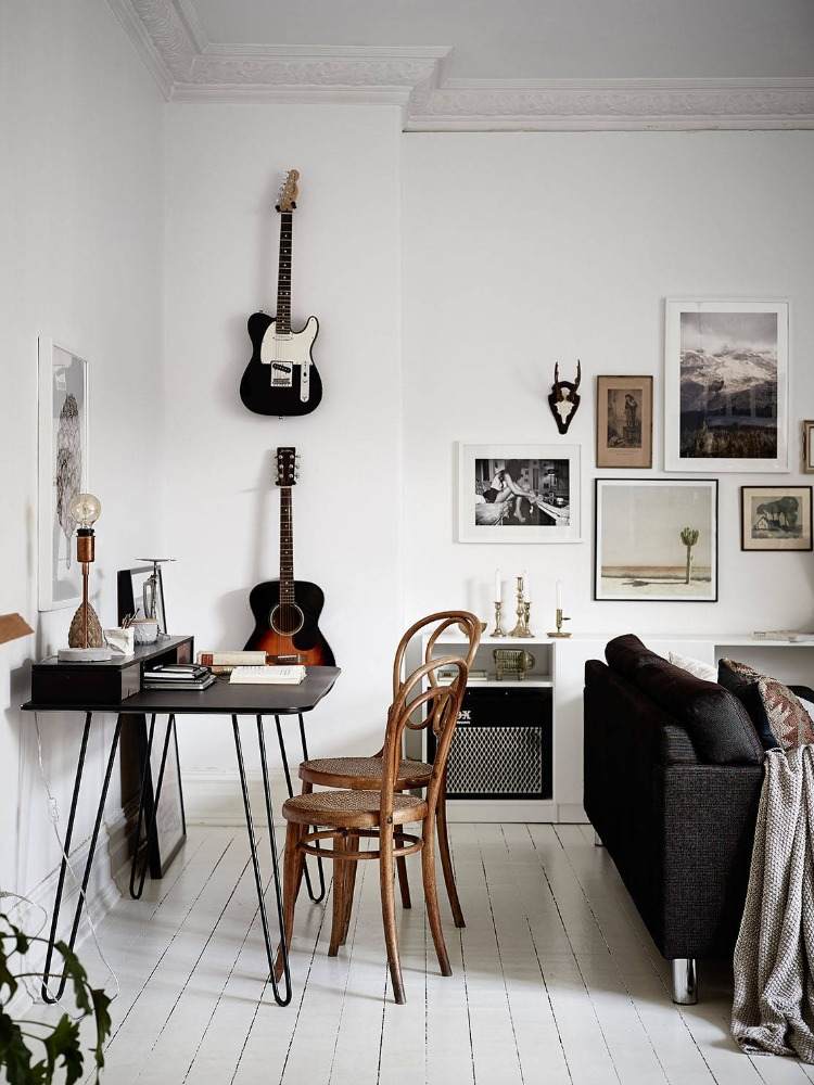 stilvoll eingerichteter wohnraum mit gitarrehalter an der wand und retro möbeln auf weißem dielenboden